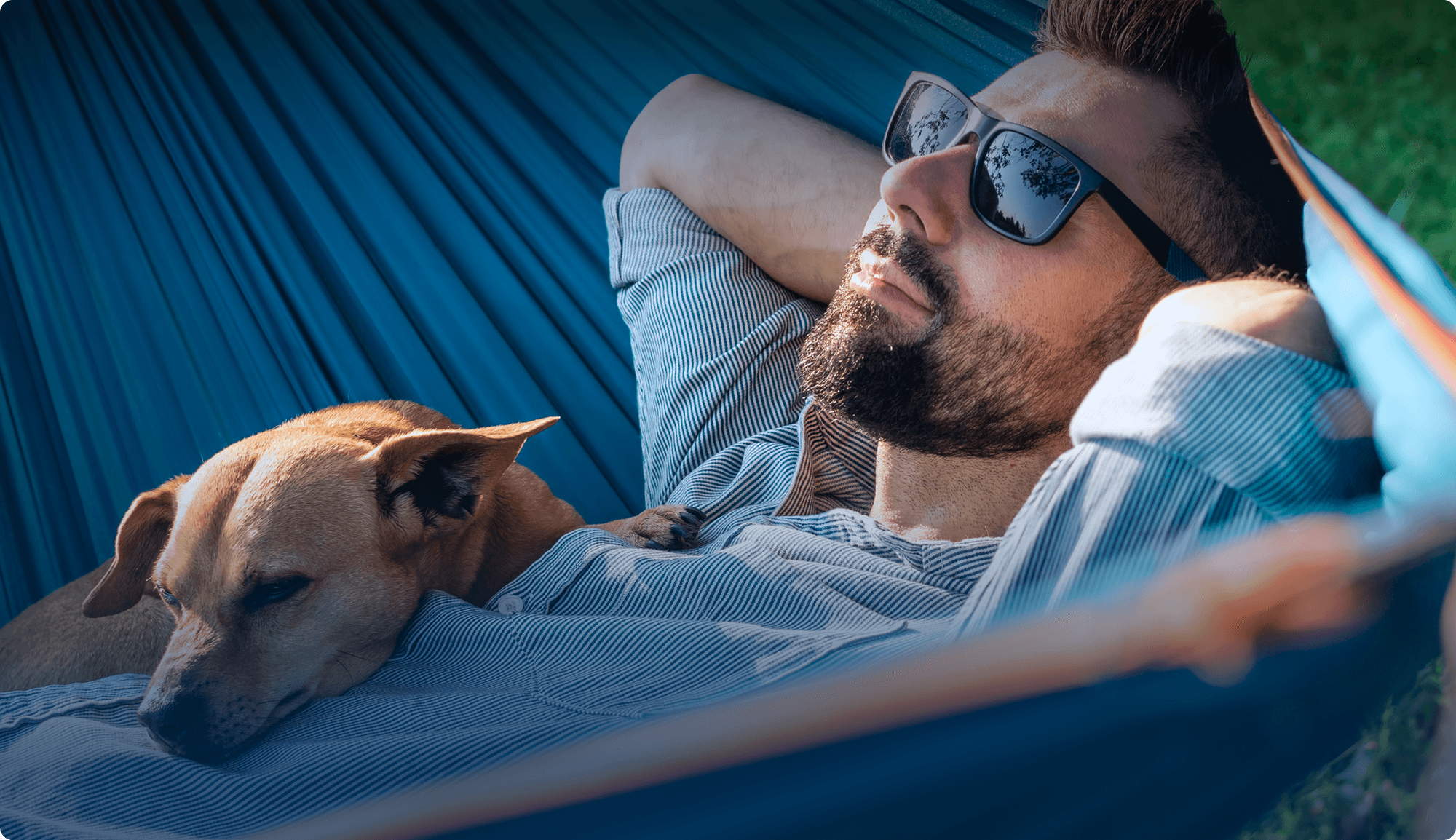 Man relaxing in a hammock with his dog